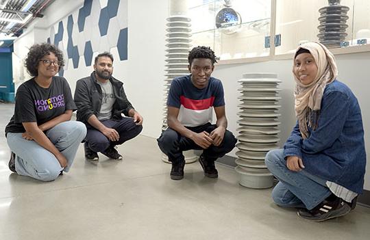 four young men and women posing in front of large ceramic insulators